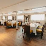Elegant cruise ship restaurant with modern furniture and wooden floor.