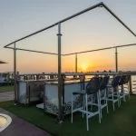 Ship's sundeck bar with sunset view and bar stools.