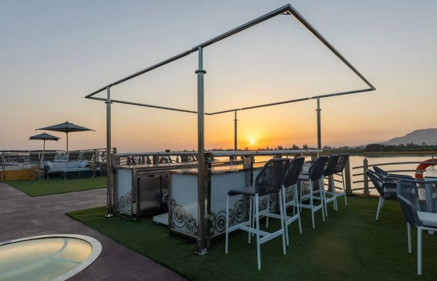 Ship's sundeck bar with sunset view and bar stools.