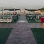 Wide view of a ship's sundeck with a bar and dining tables.