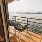Two chairs on a sunny balcony overlooking a river.