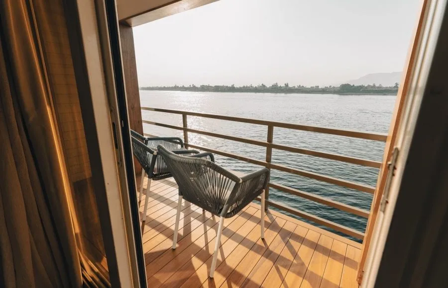Two chairs on a sunny balcony overlooking a river.