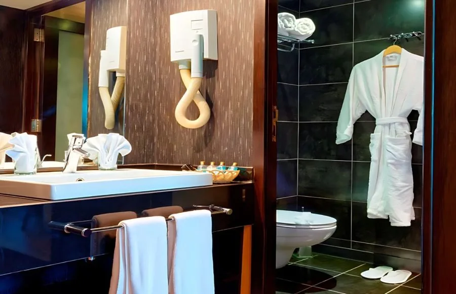 Luxurious bathroom featuring a sink, hairdryer, and plush bathrobe on the Ms Nile Premium cruise cabin ready for your comfort.