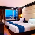 Twin-bed cabin with dark wood accents and a panoramic window on the elegant Ms Nile Premium cruise ship ensuring a restful night.