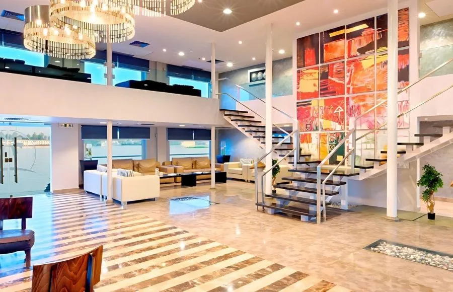 Grand lobby of the Ms Nile Premium cruise with a striking staircase, comfortable seating, and modern art reflecting its luxurious design.