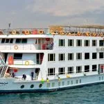 Multi-deck exterior of the luxurious ms nile premium cruise ship sailing on the Nile River under a bright sky.