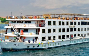 Multi-deck exterior of the luxurious ms nile premium cruise ship sailing on the Nile River under a bright sky.
