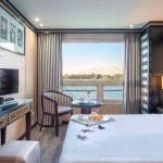 Deluxe suite on the MS Nile Style Cruise Ship with a queen bed and a picturesque view of the Nile River.