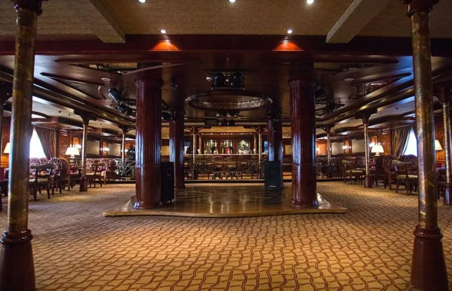 A spacious entertainment lounge with a stage, bar, and seating areas on the Princess Sarah I Nile Cruise.
