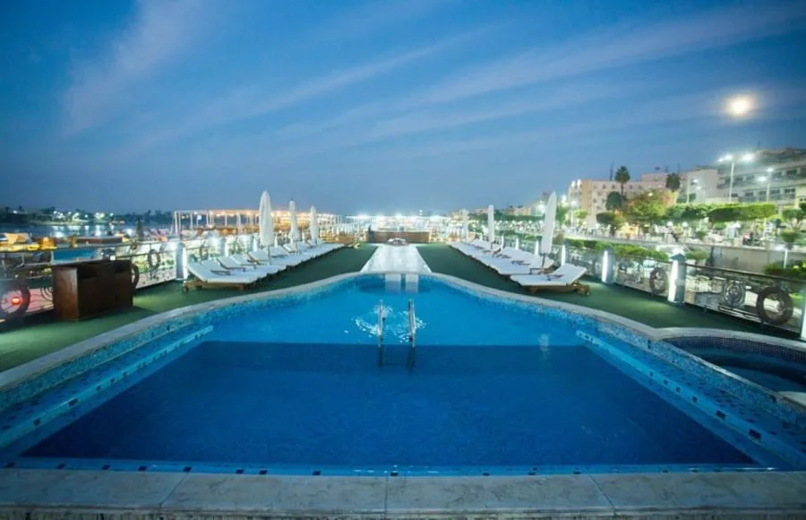 The illuminated swimming pool and sun loungers on the top deck of the Princess Sarah I Nile Cruise.