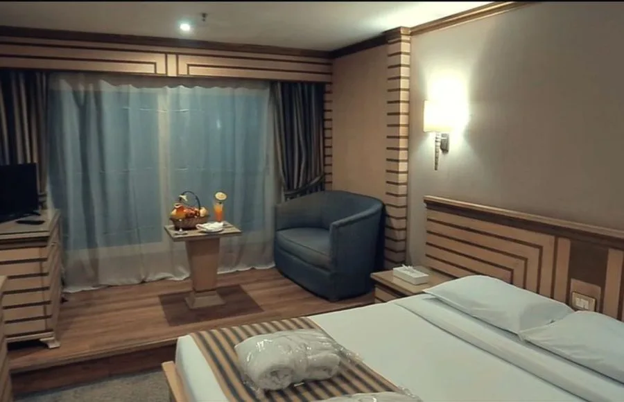 A comfortable cabin on the Princess Sarah I Nile Cruise with a single bed, a cozy chair, and a Nile view.