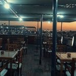 A dining area on the Princess Sarah I Nile Cruise, with a beautiful sunset over the Nile.