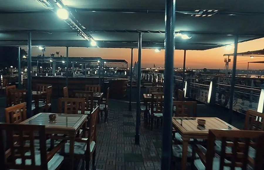 A dining area on the Princess Sarah I Nile Cruise, with a beautiful sunset over the Nile.