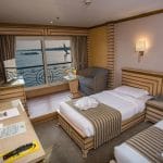 A comfortable twin cabin on the Princess Sarah I Nile Cruise with two beds and a Nile view balcony.