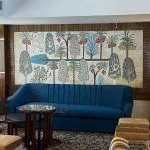 Blue velvet sofa in a cruise lobby with a large tapestry depicting trees and hieroglyphs.