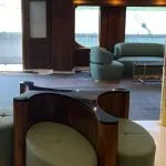 Modern seating area with green poufs and wooden counter in a ship's lobby.