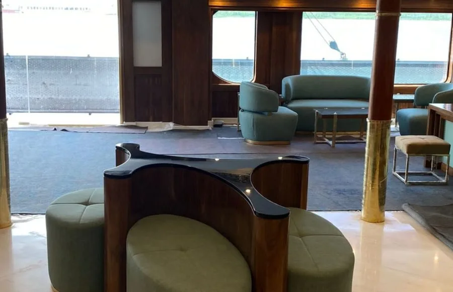 Modern seating area with green poufs and wooden counter in a ship's lobby.