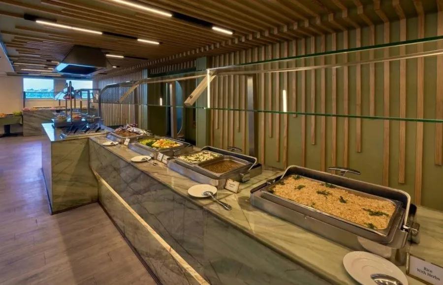 Modern twin stateroom with blue bedding, a padded headboard, and large windows showing a river view and a felucca.