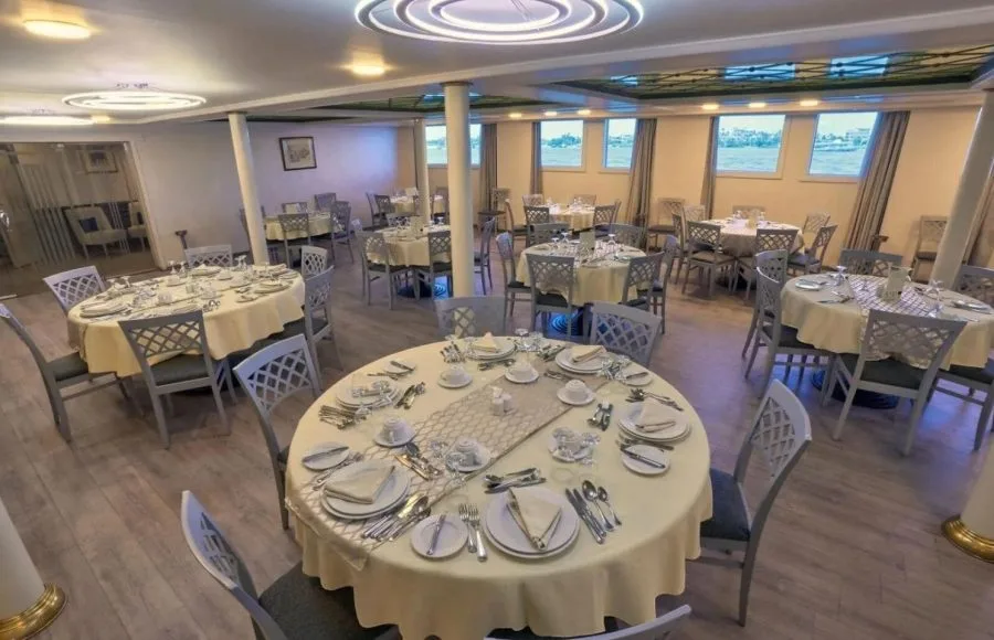 Formal dining room with multiple round tables set with white linens and elegant place settings.