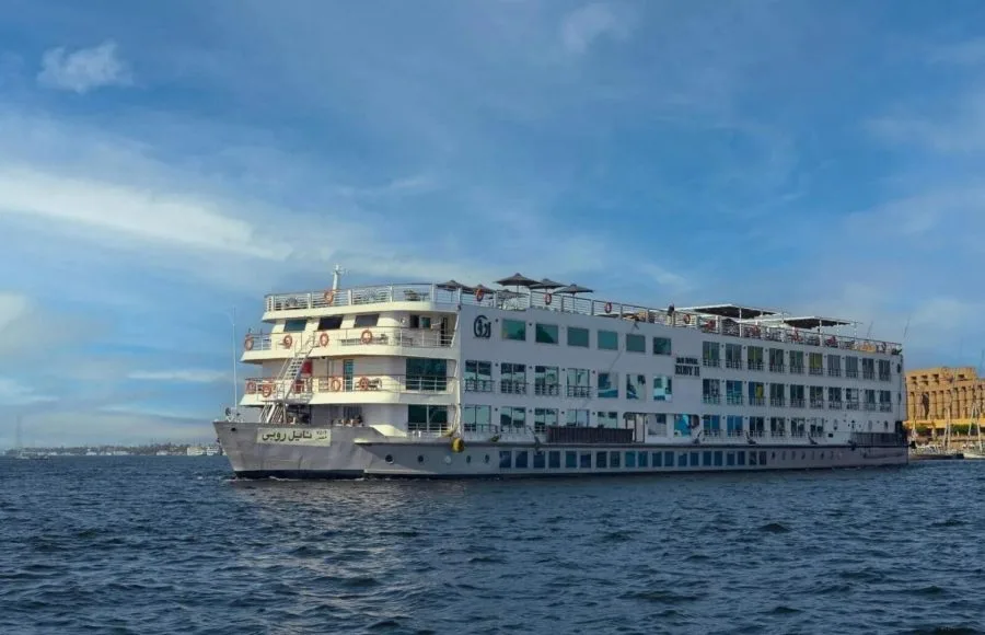 A white, multi-deck cruise ship, "Nile Goddess," sailing on the water under a clear blue sky.