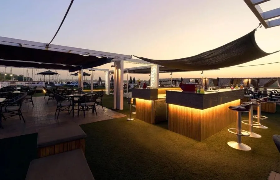 Rooftop bar at sunset with artificial turf and lounge seating.