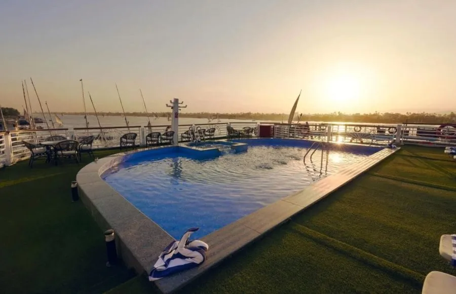 Rooftop pool area at sunset with lounge chairs, featuring a uniquely shaped pool overlooking the river.