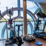 The modern fitness center on the Sonesta Moon Goddess Nile Cruise ship, equipped with various exercise machines and panoramic windows overlooking the Nile.