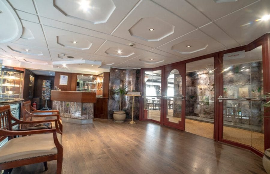 The sophisticated lobby of the Sonesta Nile Goddess Cruise with a polished wooden reception desk and a staircase leading to the upper deck.