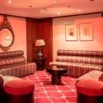 A cozy and luxurious lounge area with red seating and carpet on the Nile Goddess cruise ship, perfect for relaxation.