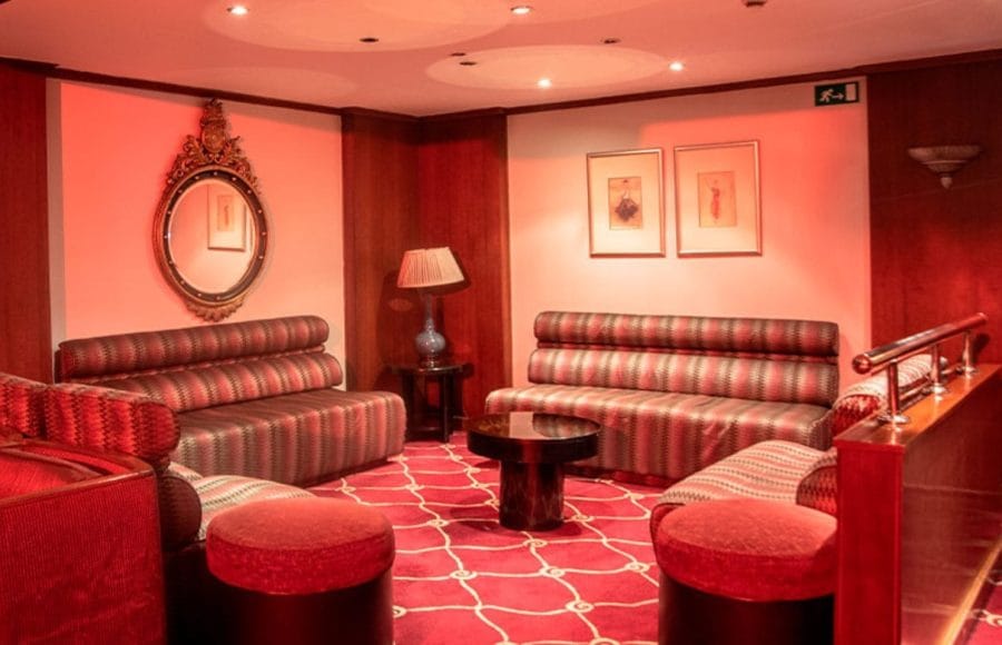 A cozy and luxurious lounge area with red seating and carpet on the Nile Goddess cruise ship, perfect for relaxation.