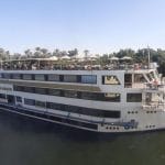 The majestic MS Nile Goddess Nile Cruise ship docked on the banks of the Nile River, with its elegant exterior and top deck visible.
