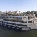 The majestic MS Nile Goddess Nile Cruise ship docked on the banks of the Nile River, with its elegant exterior and top deck visible.