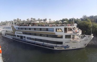 The majestic MS Nile Goddess Nile Cruise ship docked on the banks of the Nile River, with its elegant exterior and top deck visible.
