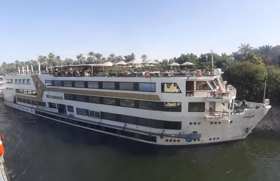 The majestic MS Nile Goddess Nile Cruise ship docked on the banks of the Nile River, with its elegant exterior and top deck visible.