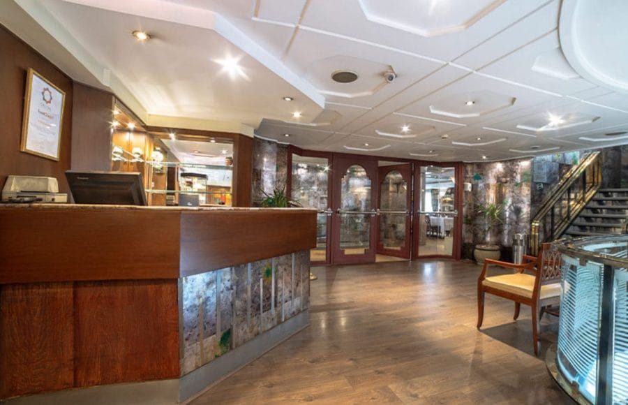 The welcoming reception area of the MS Nile Goddess Nile Cruise with a wooden front desk and a staircase.