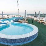 The uniquely shaped swimming pool on the sun deck of the MS Nile Goddess Nile Cruise, with lounge chairs and Nile River views.