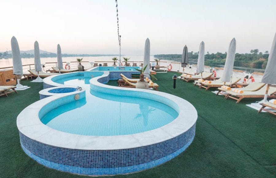The uniquely shaped swimming pool on the sun deck of the MS Nile Goddess Nile Cruise, with lounge chairs and Nile River views.
