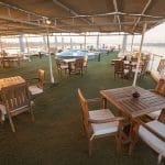 Guests dining and lounging on the sun deck of the MS Nile Goddess Nile Cruise as the sun sets over the river.
