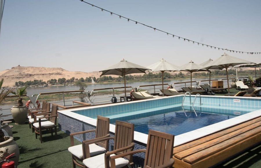 The MS Nile Goddess Nile Cruise swimming pool with the beautiful Nile River and desert landscape in the background.