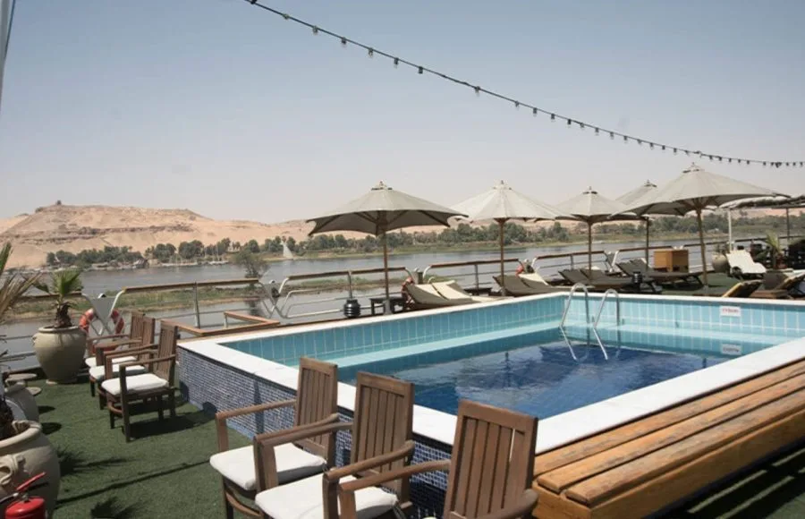 The MS Nile Goddess Nile Cruise swimming pool with the beautiful Nile River and desert landscape in the background.