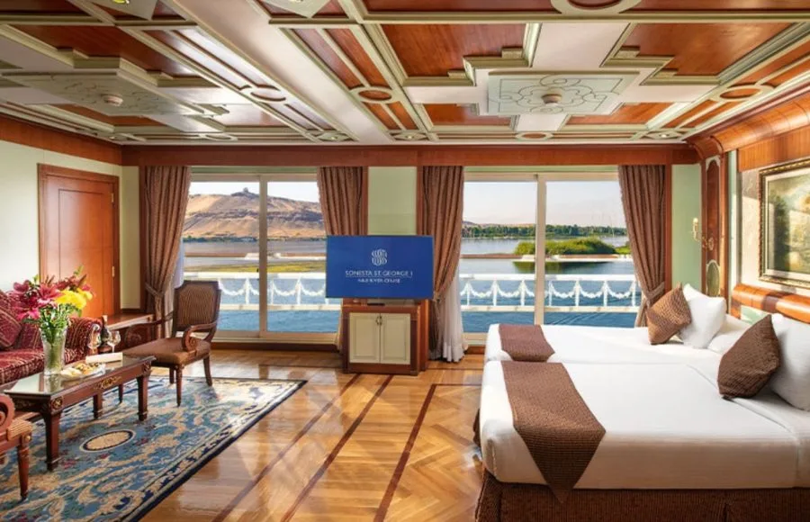 A luxurious twin-bed cabin aboard the MS Sonesta St. George Nile Cruise ship, featuring panoramic windows with stunning river views.