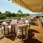 A stunning photo of the dining deck on the MS Sonesta St. George Nile Cruise ship, showcasing comfortable seating and beautiful views of the Nile River.