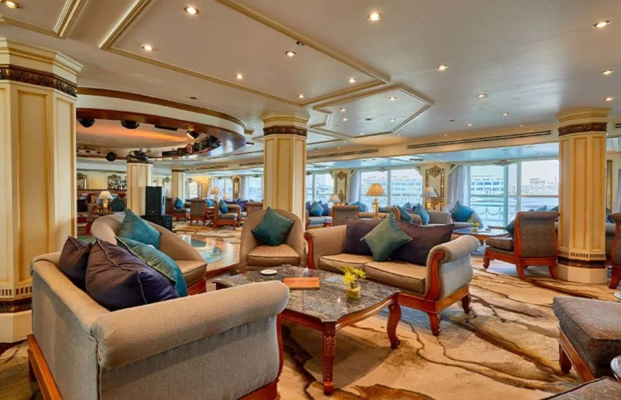 The elegant lounge on the MS Sonesta St George Nile Cruise, featuring plush sofas, comfortable armchairs, and large windows with scenic views, perfect for relaxing and socializing.