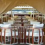 The sun deck restaurant on the MS Sonesta St George Nile Cruise ship, featuring elegant dining tables and chairs with comfortable cushions, perfect for enjoying scenic views.