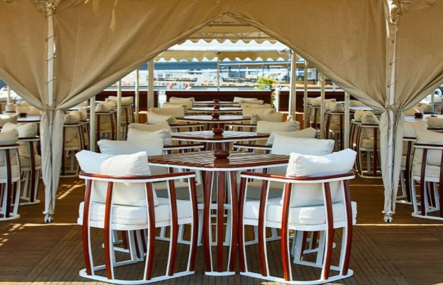 The sun deck restaurant on the MS Sonesta St George Nile Cruise ship, featuring elegant dining tables and chairs with comfortable cushions, perfect for enjoying scenic views.