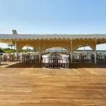 The sunny upper deck of the Ms Sonesta St George Nile Cruise ship with covered seating areas and a wooden floor.