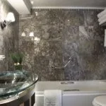 A luxurious and modern bathroom on the Sonesta Star Goddess Nile cruise ship, with a sleek glass basin, bathtub, and stylish marble-patterned walls.