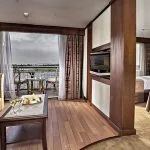 A comfortable cabin on the Sonesta Star Goddess Nile cruise ship, with twin beds, a seating area, and a private balcony overlooking the Nile.