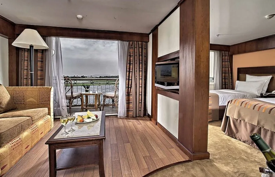 A comfortable cabin on the Sonesta Star Goddess Nile cruise ship, with twin beds, a seating area, and a private balcony overlooking the Nile.