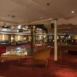 An elegant and sophisticated dining lounge on the Sonesta Star Goddess Nile cruise ship, with red velvet couches, a bar, and low tables with drinks.